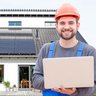Ein Mann in Arbeitskleidung vor einer Photovoltaikanlage mit einem Laptop in der Hand