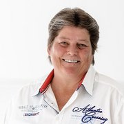 Mit einem freundlichen Gesichtsausdruck und einem weißen Hemd wirkt die Frau einladend und selbstbewusst in ihrer Präsentation.